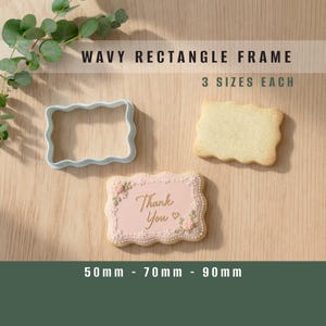 May include: A white wavy rectangle frame cookie cutter, a plain baked cookie, and a decorated pink cookie with the text Thank You and a small heart. The text WAVY RECTANGLE FRAME, 3 SIZES EACH, and 50mm - 70mm - 90mm are visible on the image.