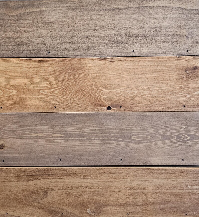 Puede incluir: Primer plano de una superficie de madera compuesta por tablas horizontales. Las tablas var&iacute;an en color, desde marr&oacute;n claro hasta gris. La veta de la madera es visible y hay peque&ntilde;os agujeros de clavos.