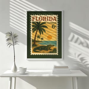 May include: Framed vintage-style Florida postage stamp art print. The artwork features a beach scene with palm trees, an alligator, and a setting sun. The text "FLORIDA U.S. POSTAGE 6&cent;" is displayed at the top of the stamp.