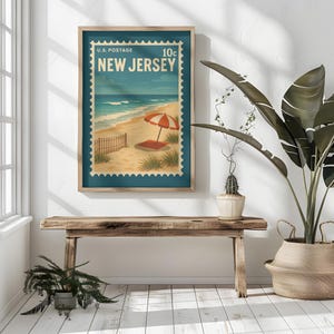May include: A rectangular wall art print featuring a vintage-style postage stamp design with the text U.S. POSTAGE 10c NEW JERSEY. The illustration depicts a sandy beach, ocean waves, a wooden fence, and a red and white striped beach umbrella.