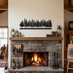 May include: A black metal silhouette of a forest scene is mounted above a stone fireplace. The fireplace has a burning fire inside. Decorative lanterns and books are on the wooden mantel. A framed tapestry with a forest scene hangs on the fireplace.