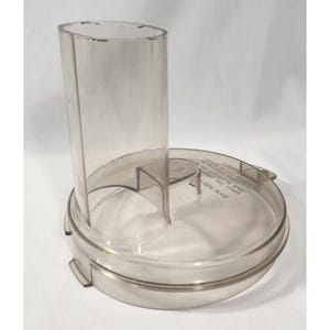 Peut inclure: Couvercle de robot culinaire en plastique transparent avec un long tube d'alimentation cylindrique. Le couvercle a une base circulaire avec un rebord et une étiquette d'avertissement. La lame n'est pas visible. Le design est fonctionnel.