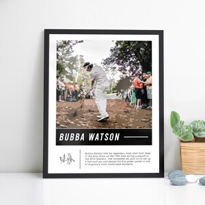 Op de afbeelding: Ingelijste print met Bubba Watson die golf speelt. De afbeelding toont Watson in een witte outfit, in volle swing. De print bevat de tekst "BUBBA WATSON" in een wit kader met een zwarte rand en een handtekening.