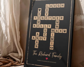 May include: Black framed family sign with a crossword design. The crossword includes the words "LAUGH, TOGETHER, KELLY, ANDY, MAX" and family names. The sign also includes the text "The Richard Family" and "FAMILY IS ALWAYS IN OUR HEART".