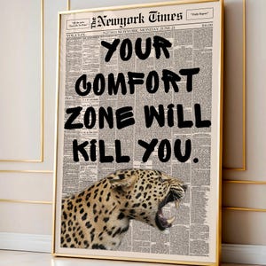 May include: Framed print featuring a newspaper background with the headline "Your Comfort Zone Will Kill You." A roaring leopard is at the bottom. The print is in a gold frame.