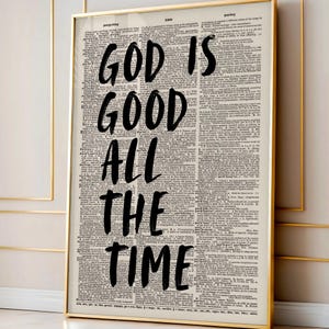 May include: A framed print with the words "GOD IS GOOD ALL THE TIME" in bold black lettering. The background is a vintage dictionary page, and the frame is gold.
