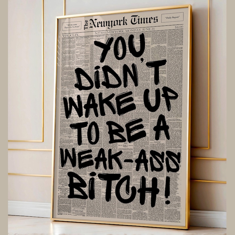 May include: Framed print featuring a newspaper background with the headline "The Newyork Times." Bold black text reads "YOU DIDN'T WAKE UP TO BE A WEAK-ASS BITCH!" The print is encased in a gold frame.
