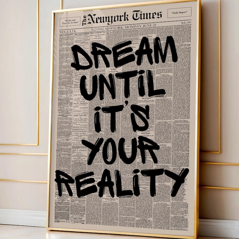 May include: A framed print featuring a vintage newspaper background with the words "DREAM UNTIL IT'S YOUR REALITY" in bold black lettering. The print is in a gold frame, adding a touch of elegance to the motivational message.