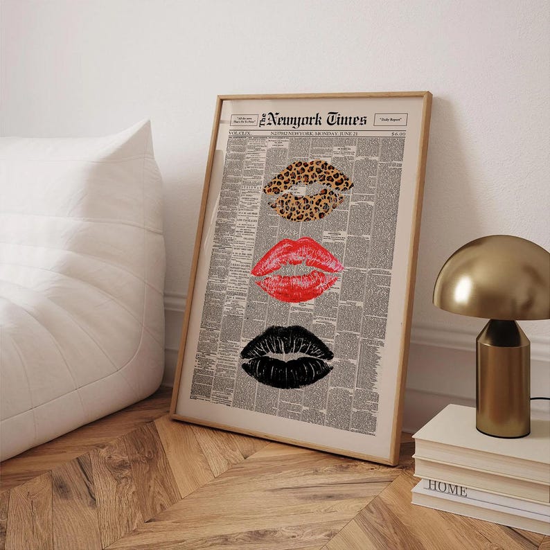 May include: Framed print featuring three sets of lips in leopard print, red, and black, set against a newspaper background. The top of the print reads "New York Times". The artwork is displayed in a light-colored wooden frame.