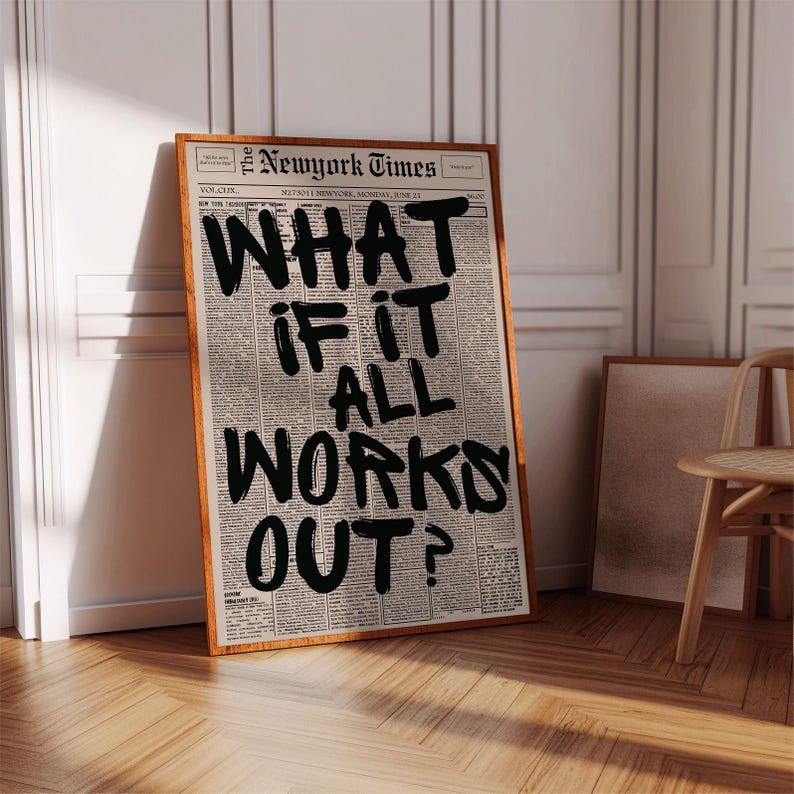 K&ouml;nnte beinhalten: Ein gerahmter Kunstdruck mit dem Layout einer alten Zeitung und dem fetten, handgeschriebenen schwarzen Text WHAT IF IT ALL WORKS OUT?, der &uuml;ber den Spalten zentriert ist. Der Druck ist in einem d&uuml;nnen Holzrahmen mit hellbraunem Finish.