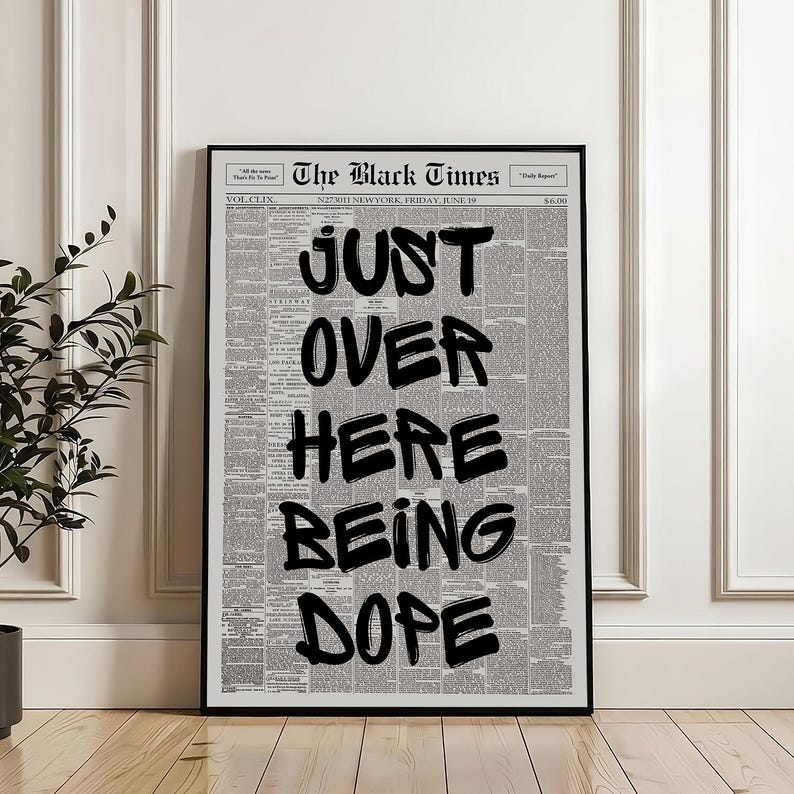 Puede incluir: Una impresi&oacute;n de arte mural vertical enmarcada que presenta la portada de un peri&oacute;dico titulada The Black Times. El fondo es una cuadr&iacute;cula densa de texto peque&ntilde;o en negro sobre una p&aacute;gina blanca. Letras grandes, negritas y con estilo de pincel negro se superponen al texto, formando JUST OVER HERE BEING DOPE.