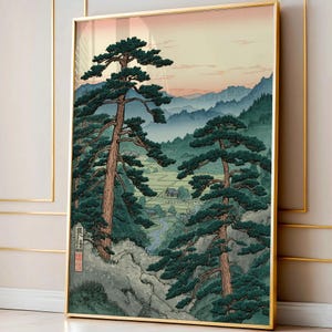 以下が含まれることがあります： 日本の風景の額装されたアートプリント。このアートワークは、前景にそびえ立つ松の木、背景に谷と山々を描いています。カラーパレットには、緑、青、柔らかなピンクの空が含まれています。プリントは金のフレームに入っています。