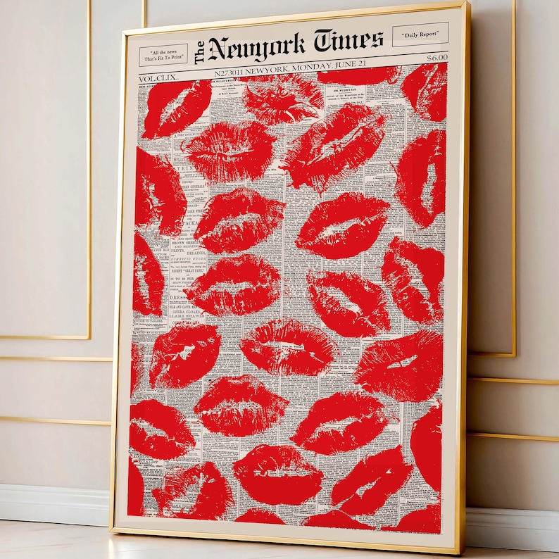 May include: A framed print featuring a collage of red lipstick kiss marks over a vintage newspaper background. The newspaper is titled "The New York Times" with the date "Monday, June 21". The print is in a gold frame.