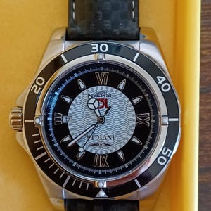May include: A stainless steel Invicta watch with a black and silver face. The watch features a black bezel with white numerals and a black leather band. The watch face displays the Invicta logo and is water resistant to 200 meters.