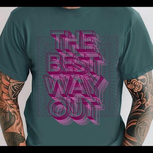 Könnte beinhalten: Türkisfarbenes T-Shirt mit dem Text "THE BEST WAY OUT" in einem 3D-Design in Pink und Lila. Der Text ist über einem Rastermuster angeordnet. Das Shirt hat kurze Ärmel und einen Rundhalsausschnitt.
