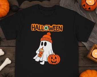 May include: Black t-shirt with a Halloween graphic. The design features a ghost wearing an orange beanie and holding a pumpkin spice drink, with a carved pumpkin and the word "HALLOWEEN".