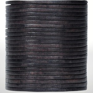 May include: A stack of dark gray, circular, leather bracelets. The bracelets are stacked on top of each other, creating a cylindrical shape. The leather has a textured appearance.