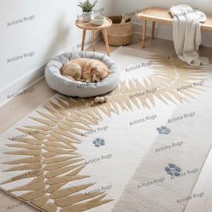 May include: A beige and white area rug with a stylized feather design in tan. The rug features small blue flower accents. A dog bed with a sleeping dog is in the upper left corner.