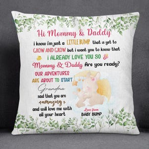 May include: White square pillow with a floral border and text that reads "Hi Mommy & Daddy" and "Love from BABY BUMP." The pillow features a graphic of two bunnies and a moon. The text also includes the phrases "I ALREADY LOVE YOU SO" and "OUR ADVENTURES ARE ABOUT TO START."