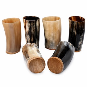 Peut inclure: Un ensemble de six gobelets fabriqués en corne naturelle présentant des motifs organiques distincts dans des tons crème, beige, brun et noir. Chaque récipient possède une finition polie et une base circulaire en bois pour la stabilité.
