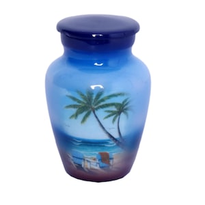 Peut inclure: Urne en céramique bleue avec couvercle, représentant une scène de plage avec des palmiers, l'océan et une chaise longue. L'urne présente un dégradé de bleus, avec un couvercle bleu foncé et un corps bleu clair.