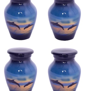 May include: Four small, blue urns with a glossy finish. Each urn features a painted scene of dolphins leaping from the ocean at sunset. The lids are dark blue, and the urns have a classic, rounded shape.