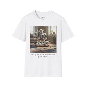 May include: White t-shirt featuring a colorful image of a robot model kit. The image includes the text "Let your inner child build giant robot."