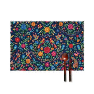 Puede incluir: Un mantel individual rectangular con fondo azul oscuro que presenta un patrón floral simétrico y vibrante con flores rojas, naranjas y azules, follaje verde, aves coloridas y mariposas, junto a una cuchara y palillos de madera oscura.