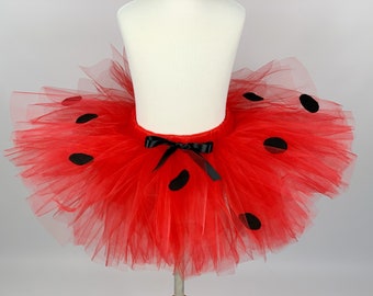 May include: Red tulle tutu skirt with black polka dots and a black satin bow.