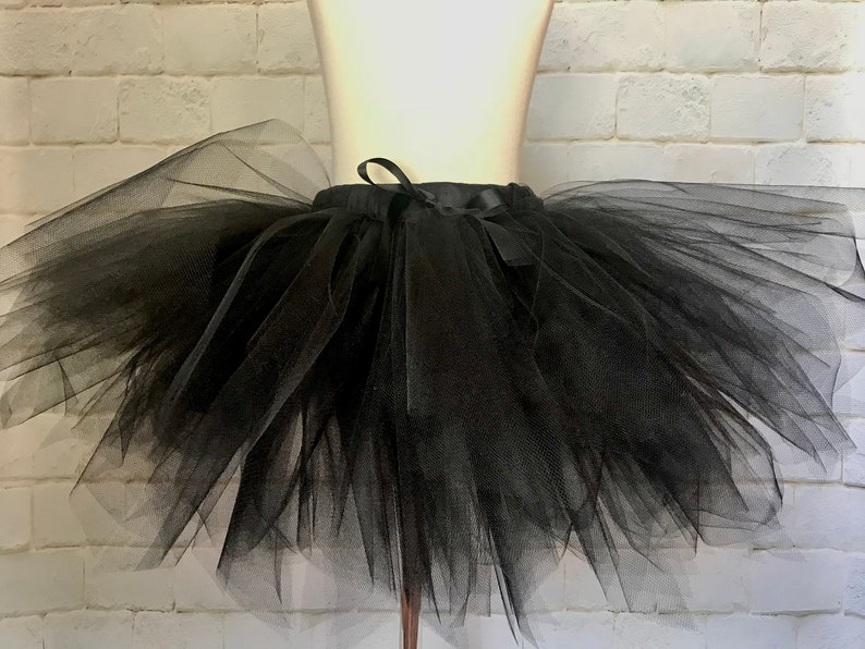 May include: A black tulle tutu skirt with a satin ribbon tie. The skirt is full and fluffy, perfect for a dance recital or costume.