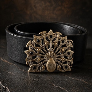 May include: A black leather belt with a decorative brass buckle in the shape of a peacock. The buckle features intricate detailing and a vintage aesthetic. The belt is shown on a dark, textured surface.