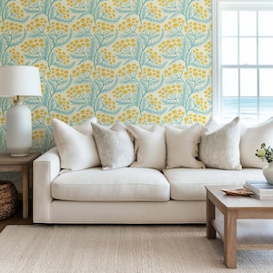 a living room with a white sofa, a wooden coffee table, and a lamp. The walls are decorated with a floral wallpaper pattern in shades of yellow and green.