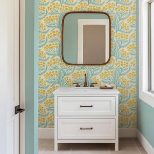 a bathroom with a white vanity and a mirror above it, set against a wall with a floral pattern in shades of yellow and green.
