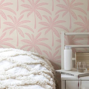 Tropical Preppy Palm Tree Wallpaper in Pink and Cream styled in a modern bedroom with bed and side table