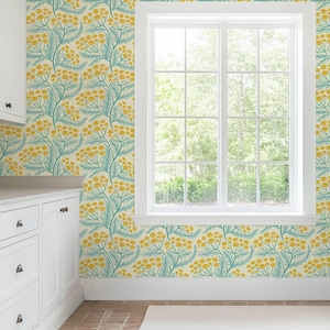 a bright and airy kitchen with a large window that provides a view of the outdoors. The walls are adorned with a vibrant floral wallpaper pattern in shades of yellow and green, creating a cheerful and lively atmosphere. The kitchen features white cabinets and drawers, complementing the overall color scheme of the room.