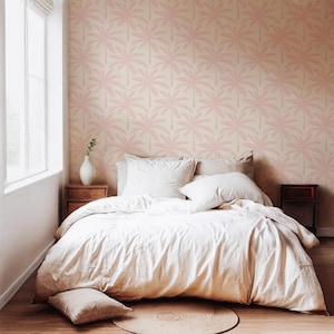 Puede incluir: Un dormitorio con papel tapiz de patr&oacute;n repetitivo de hojas de palmera en rosa claro. La cama est&aacute; vestida con una funda n&oacute;rdica y almohadas de color crema. Un jarr&oacute;n blanco descansa sobre una mesita de noche de madera y una alfombra redonda.