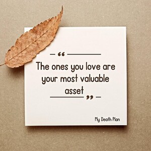 May include: A white square card with the quote "The ones you love are your most valuable asset" in black text. A dried brown leaf rests on the card. The text "My Death Plan" is at the bottom.
