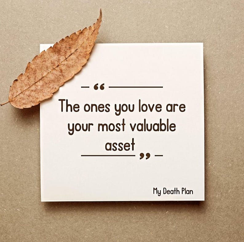 May include: A white square card with the quote "The ones you love are your most valuable asset" in black text. A dried brown leaf rests on the card. The text "My Death Plan" is at the bottom.