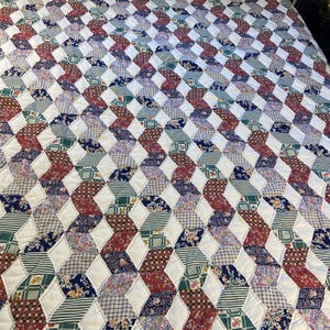 May include: A patchwork quilt featuring a repeating geometric pattern of white diamonds interspersed with various fabric squares in shades of red, blue, green, and yellow, showcasing diverse floral, plaid, and striped prints throughout the design.