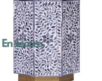 May include: A hexagonal side table featuring a white and grey floral leaf inlay pattern across its vertical panels. The table stands on a solid gold-toned hexagonal base. The text "Endecore" is printed in green on the left side of the table.