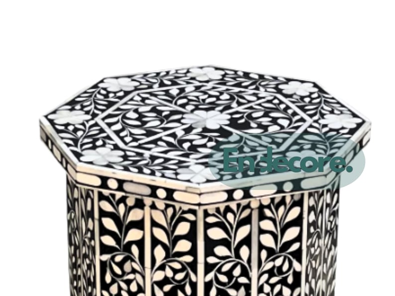 May include: Black and white octagonal side table with floral inlay design. The table features a detailed pattern of white flowers and leaves against a black background. The table's design is symmetrical and decorative.