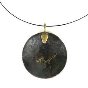 Puede incluir: Un collar con un colgante redondo negro, una anilla de metal dorado y una inscripci&oacute;n dorada que dice "M. Bryan".