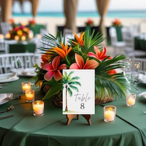 May include: A table setting with a green tablecloth, tropical flower arrangement, and a table number card. The card features a palm tree illustration and the text "Table 8". Lit candles add ambiance to the scene.