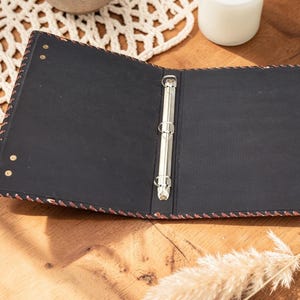 Open leather pentagram binder showing inner pages and ring mechanism, journal interior