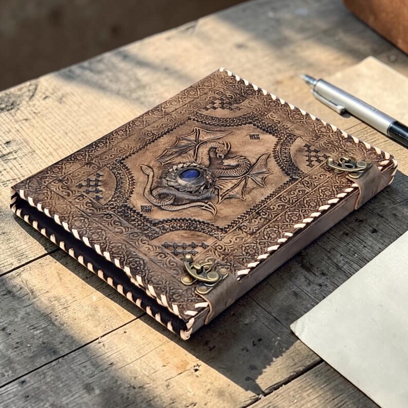 Leather dragon embossed A4 ring binder journal with blue gemstone accent, placed on rustic wooden table with parchment fabric, cinematic warm lighting and high detail fantasy stationery