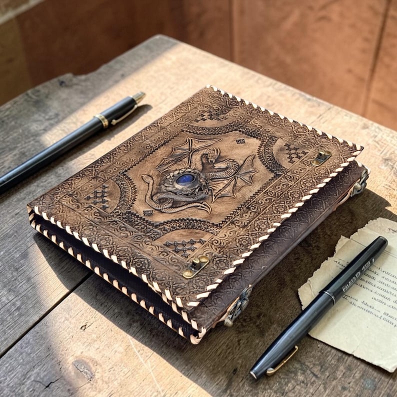 Etsy product thumbnail of leather dragon binder journal, high contrast lighting highlighting embossed details and gemstone