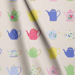 May include: A light beige fabric featuring a repeating pattern of various teapots in multiple colours including green, yellow, blue, and pink. Some teapots are solid colours, while others feature floral or small dot designs with gold-coloured lids.
