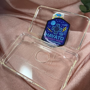 Può includere: Custodia trasparente per telefono con toppa blu scuro. La toppa presenta il testo "HAYATO" e "MIDNIGHT MODS" in bianco, oltre a un design a forma di croce e fulmini.
