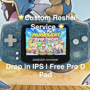 May include: A teal Game Boy Advance handheld console with a glittery finish. The screen displays the Mario Kart: Super Circuit game. The text on the console reads "Custom Reshell Service" and "Drop in IPS I Free Pro D Pad."