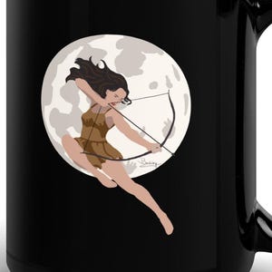 May include: Black ceramic mug featuring a graphic of a woman archer with a bow and arrow, set against a full moon backdrop. The archer is depicted in a dynamic pose, wearing a brown outfit. The mug has a large handle.
